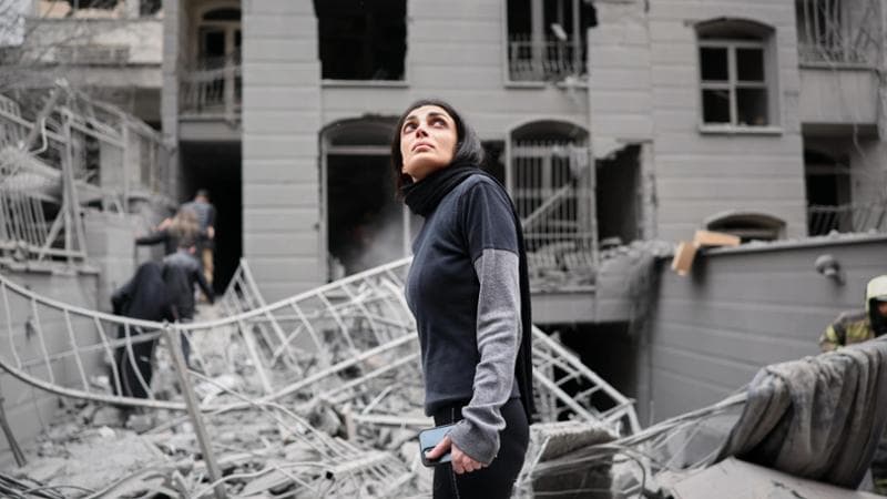 Una donna tra le macerie di un palazzo colpito a Teheran&nbsp;
