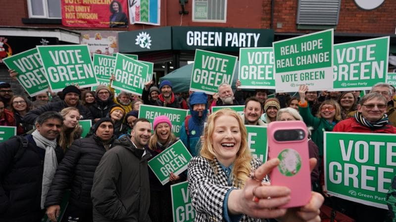 Il 20 febbraio Zack Polanski (sulla sinistra, accanto alla donna con il cappello rosa) e la candidata verde Hannah Spencer (in primo piano) festeggiano la vittoria di lei 
nelle elezioni Gorton & Denton, alla periferia di Manchester.  Loannis Alexopoulos/ Getty Images