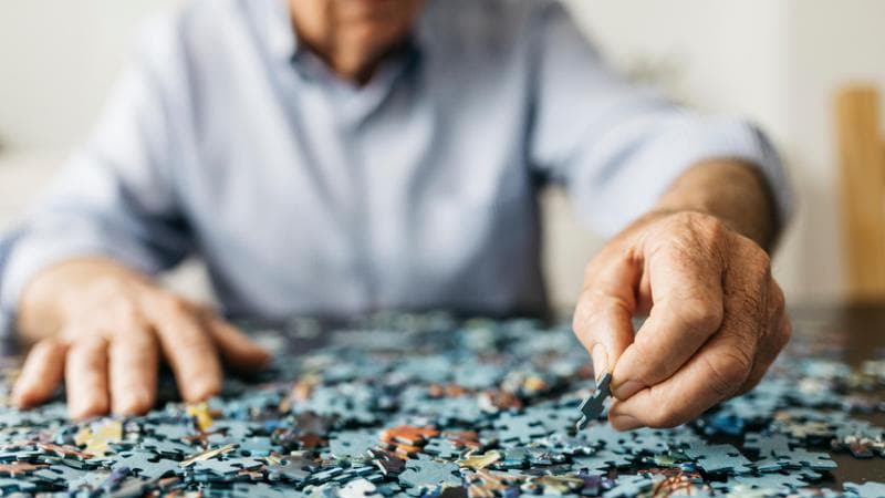 Senior retired man doing a puzzle, only hands.
