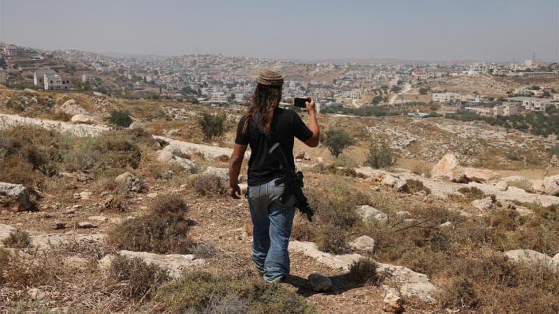 Un colono filma le terre palestinesi nei pressi di Hebron, in una delle aree della Cisgiordania dove gli attacchi negli ultimi mesi si sono intensificati (AFP via Getty Images)