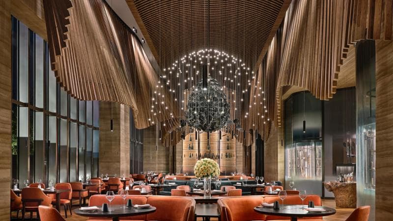 Fiamma, ristorante del MGM Qingdao hotel in Cina. Un elemento in legno scanalato attraversa il soffitto caratterizzando lo spazio (foto Owen Raggett)
