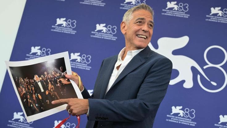 George Clooney a Venezia con la foto che gli hanno regalato i fotografi della Mostra per premiarlo della sua disponibilità. Il direttore della Mostra Barbera gli ha conferito il pass dei fotografi