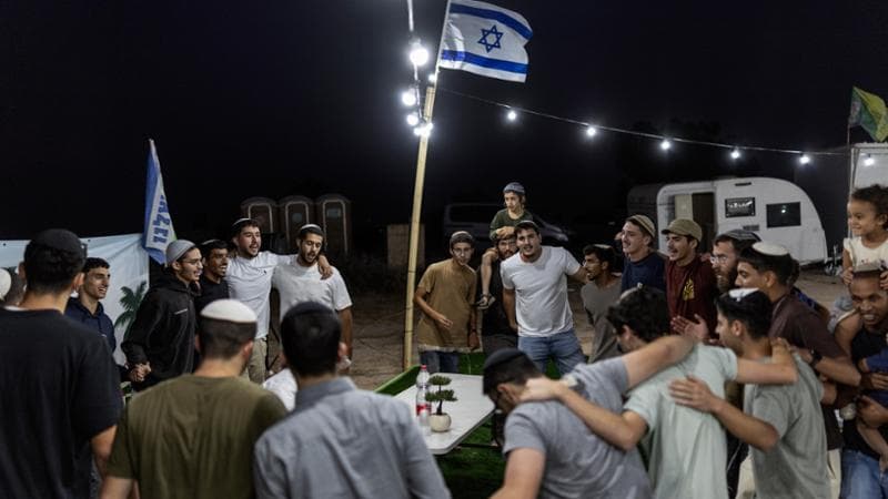 I coloni ballano e cantano attorno a un tavolo durante un momento di celebrazione religiosa nel nuovo avamposto di "Halitzei Gaza" (Pionieri di Gaza)